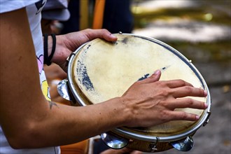 Detail of musician playing tambourine during a samba performance at carnival in the streets of