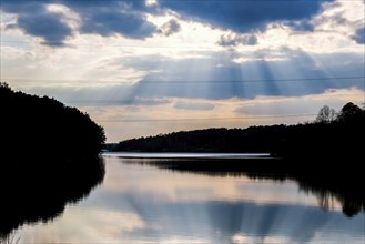 Scenic View Of Calm Lake At Sunset. River weather sun rays. Clouds. Mirror effect. Nature