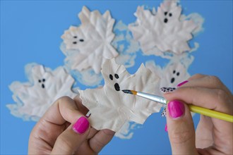 Maple leaf with painted face as decoration for autumn Halloween holiday celebration. Halloween