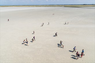 Mont Saint Michel, France, July 25, 2018: Group of hikers in the bay at low tide, Europe