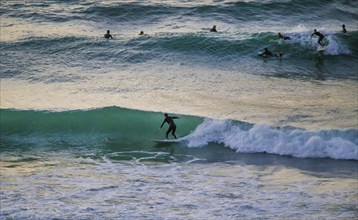 Surfer on board riding the wave, another on next wave! Tel Aviv, evening