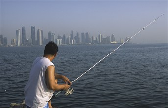 13.09.2010, Doha, Qatar Qatar, A man fishing on the promenade along Al Corniche Street with a view