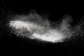 Bizarre forms of white powder explosion cloud against black background.White dust particles splash