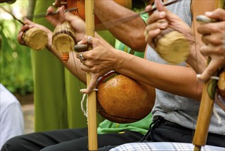 Several musicians playing an Afro Brazilian percussion musical instrument called the berimbau