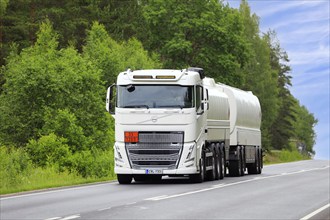 White Volvo FH tank truck transports gasoline fuel, ADR code 33-1203, on rural highway on a day of