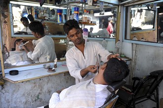 08.12.2011, Mumbai, Maharashtra, India, Asia, A barber shaves a customer in a small men's parlour