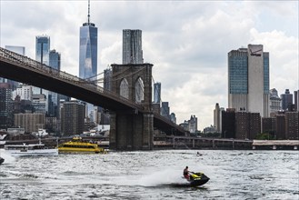 New York City, USA, June 24, 2018: Cityscape of Downtown of Manhattan and Brooklyn Bridge with jet