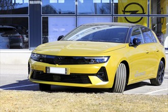 New, yellow Opel Astra parked outside a dealership. The new 6th generation of Astra is available