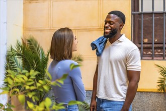 Multi-ethnic african and caucasian couple talking relaxed and smiling in the street