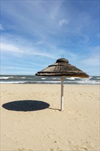 Straw beach rattan parasol at the empty beach with blue sky backgrounds sea ocean coast. Relaxing