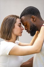 Vertical side view of multi-ethnic lovers about to kiss facing each other with eyes closed