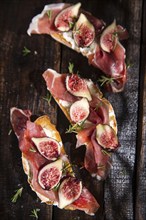 Presentation on wooden table bruschetta with figs and prosciutto