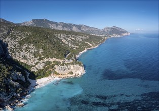 Aerial view of the rugged mountainous coast near Cala Gonone with turqouise water and small white