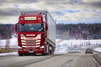 Customized red Scania 500 S super truck pulls semi trailer in traffic on a day of winter. Salo,