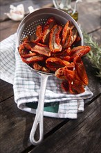 Presentation portion of dried tomatoes with rosemary in small colander