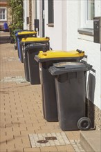 Various rubbish bins standing on the pavement in front of residential buildings, Hildesheim, Lower