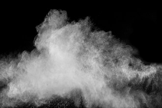 Freeze motion of white dust particles on black background. White powder explosion