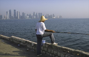 13.09.2010, Doha, Qatar Qatar, A man fishing on the promenade along Al Corniche Street with a view