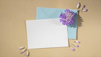 Composition with empty paper note and envelope beautiful spring blue flowers on beige background.