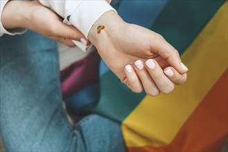 Closeup of young caucasian millennial hippie woman with a rainbow flag in heart shape painted in