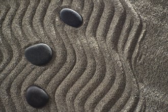 Drawings on light gray sand and black stones in a small Zen garden