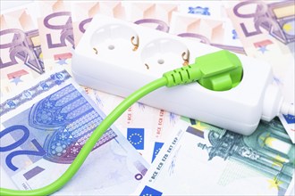 The photo shows a green power cable with euro banknotes