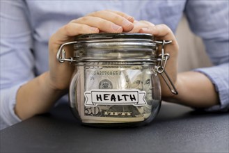 Unrecognizable woman holding Glass jar full of American currency dollars cash banknote with text