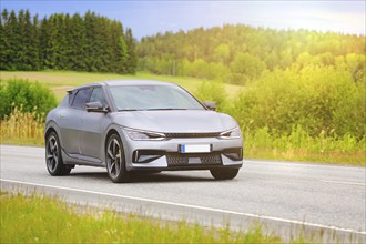 Silver Kia EV6 battery electric car at speed on highway in golden summer sunlight