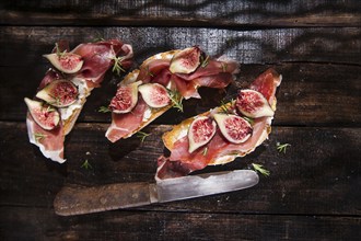 Presentation on wooden table bruschetta with figs and prosciutto