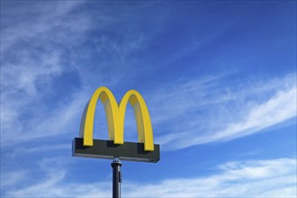 McDonald's logo against blue sky and white fair weather clouds at McDonald's restaurant in Salo,