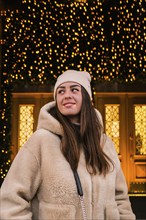 Young beautiful woman walking in new year decorated street market outdoor. Atmosphere of