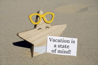 VACATION IS A STATE OF MIND text on paper greeting card on background of funny starfish in glasses