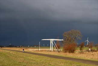 Cyclist tries to stay ahead of a heavy shower on a bicycle path in the Dutch province Friesland