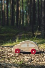 Wooden toy car on greenery forest background. Eco-car concept World car free day electric vehicle