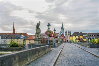 Pedestrian Old main bridge and panorama of medieval Wurzburg town. Flower decarations and ancient