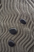 Drawings on light gray sand and black stones in a small Zen garden