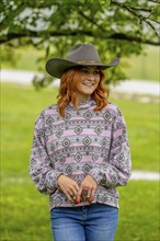 A beautiful redhead model poses in a country setting wearing cowgirl attire