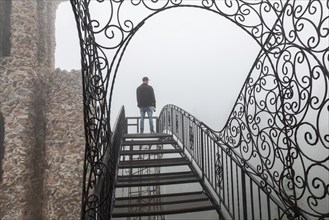 Rye, Colorado, A main stands on an open stairway, high above the ground, at Bishop Castle on a