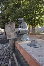 Sculpture The Newspaper Reader by Franz Werner Müller Steinfurth 1952 at Juliusplatz, hat, sitting,