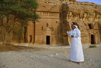 Rawi, storyteller, in front of the Nabataean tombs at the rock Qasr Al-Bint, Hegra or Madain Salih,