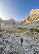 Mountaineer on a hiking trail, rocky mountain peaks Blaueisspitze and Hochkalter at sunrise,