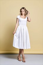 Beautiful joyful young woman in white sundress posing in studio