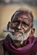 CHENNAI, INDIA, FEBRUARY 10, 2014: Unidentified old fisherman smoking on Marina beach in Chennai,