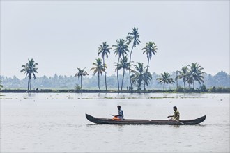 KERALA, INDIA, MAY 5, 2010: Unidentified indian men in small boat in backwaters. Kerala backwaters