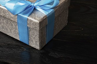 Gift birthday Christmas present concept, silver gift box with blue ribbon on dark wooden background