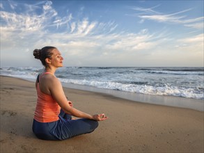 Young sporty fit woman doing yoga, meditating and relaxing in Padmasana Lotus Pose) with chin mudra