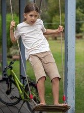 Boy swinging standing on children's swing at shed, Germany, Europe