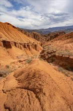 Eroded mountain landscape with sandstone cliffs, canyon with red and orange rock formations,