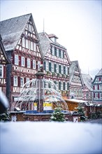 Half-timbered house backdrop on a snow-covered Christmas market with winter decorations, Black