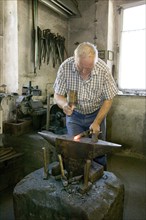 Blacksmith at the Demitz-Thumitz granite works. The granite processing tools have to be reforged,